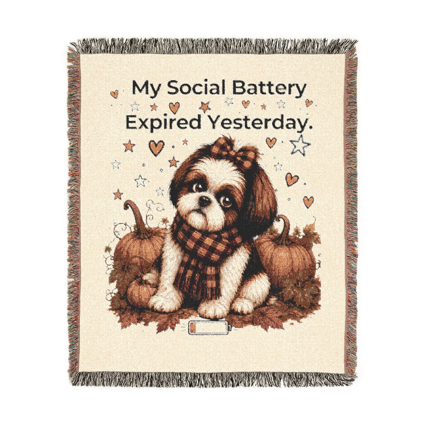 A square woven throw blanket with fringe edges, featuring a cream background and a central illustration of a small brown-and-white dog sitting between pumpkins and autumn leaves. Above the dog, the text reads, 'My Social Battery Expired Yesterday.