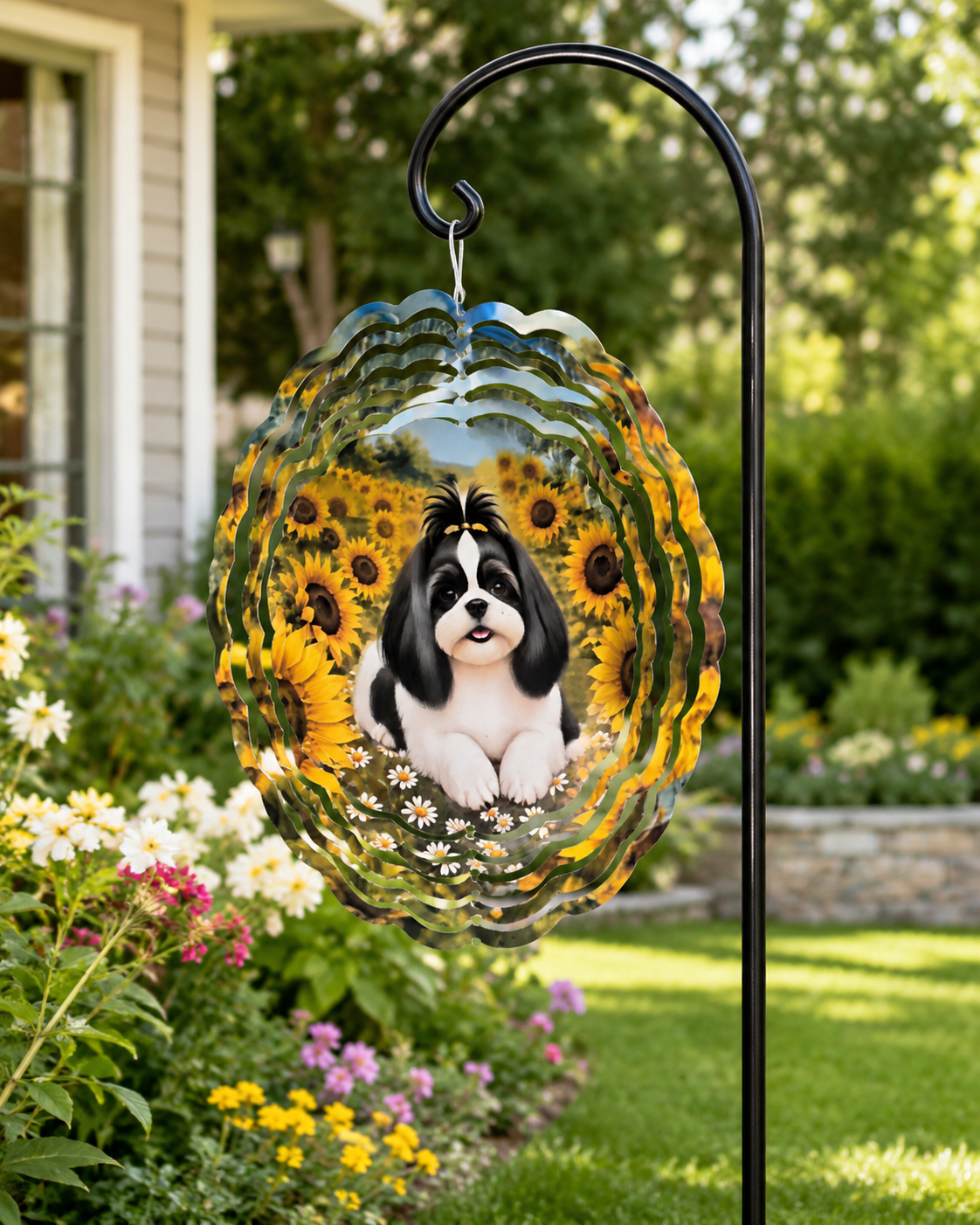 A decorative garden flag hanging from a black metal stake in a sunny backyard garden. The flag features a black and white dog sitting among yellow sunflowers and small white flowers, with a blue sky and clouds at the top.