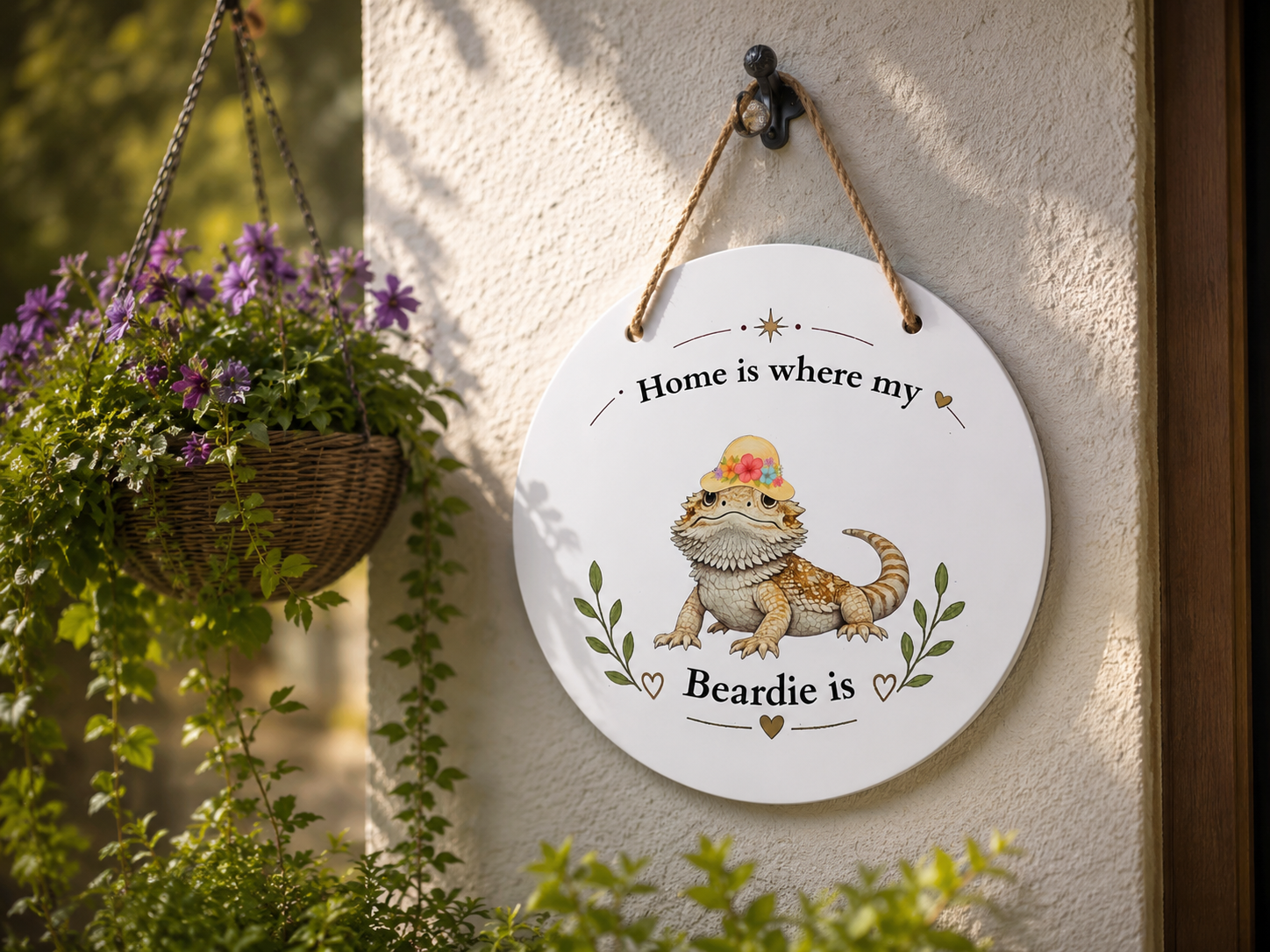 Decorative sign with a bearded dragon illustration and text 'Home is where my Beardie is' hanging on a wall with plants.