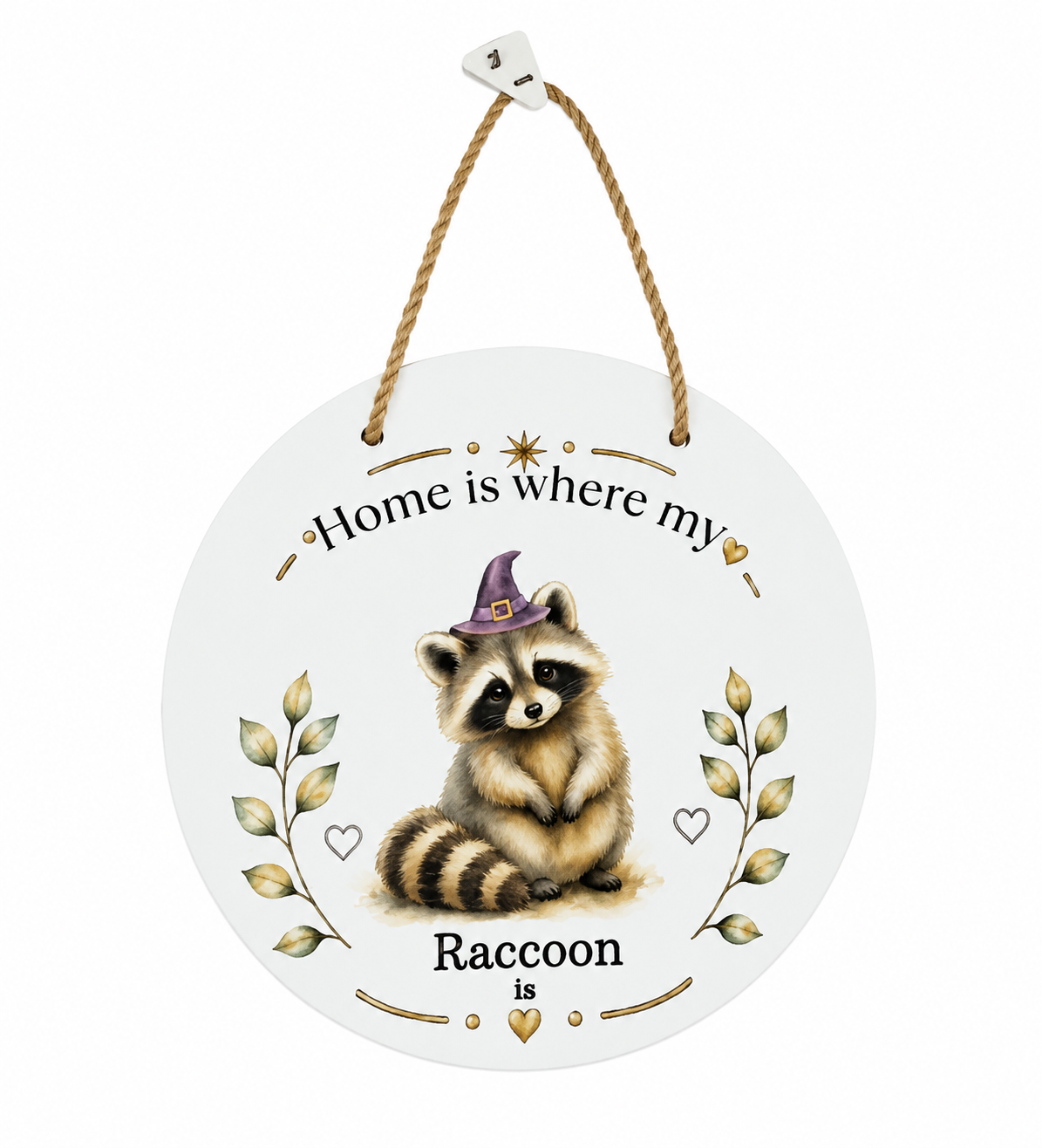 A round white hanging wall ornament with a rope hanger, featuring an illustrated raccoon wearing a purple witch hat, with the text 'Home is where my Raccoon is' and decorative gold leaf accents.