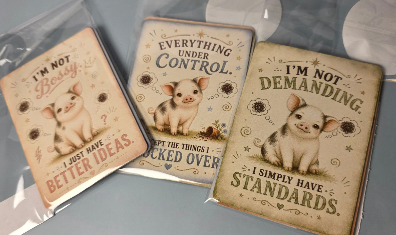 Three mini pig-themed magnets illustrations and humorous text on a gray background 