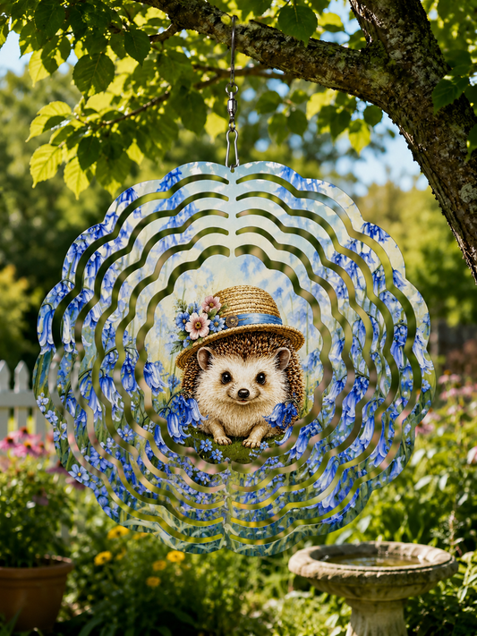 A decorative hanging garden ornament shaped like a hedgehog in a straw hat, surrounded by blue floral swirls and set against a real garden background with trees, plants, and a birdbath.