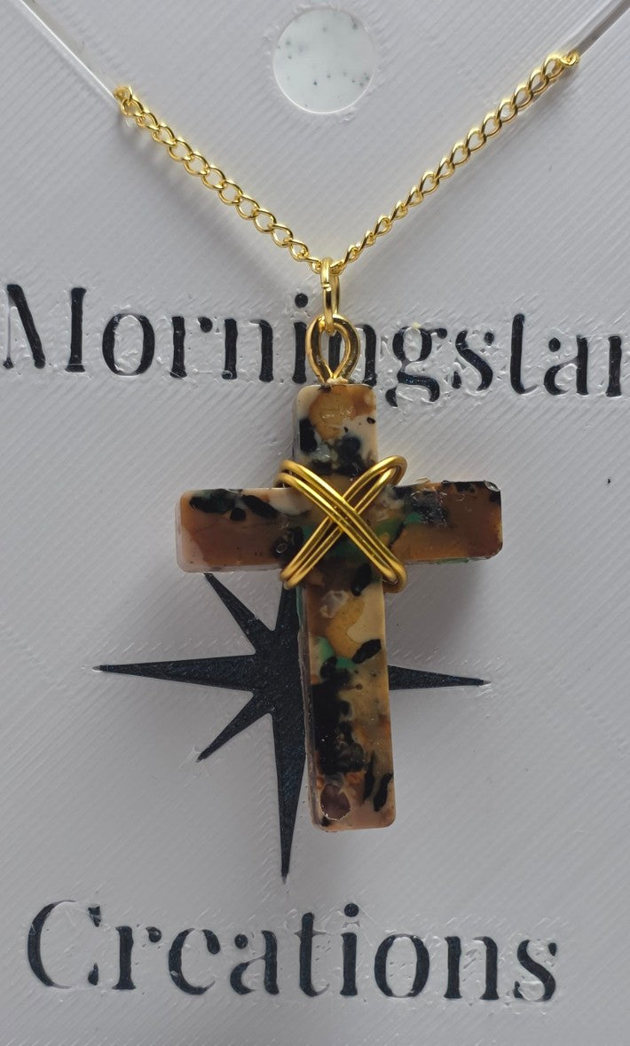 A gold chain necklace with a cross pendant made of brown and black marbled stone, wrapped with a gold X at the top, displayed on a branded card that reads 'Mornigstar Creations'.